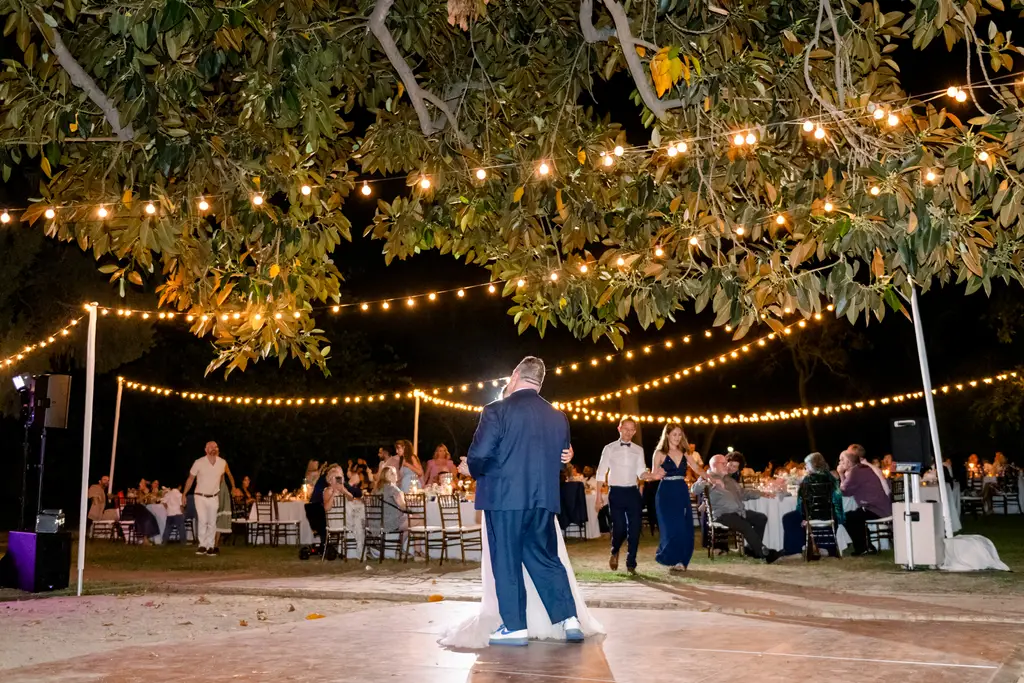 Night outdoor wedding reception with string lights and dancing.
