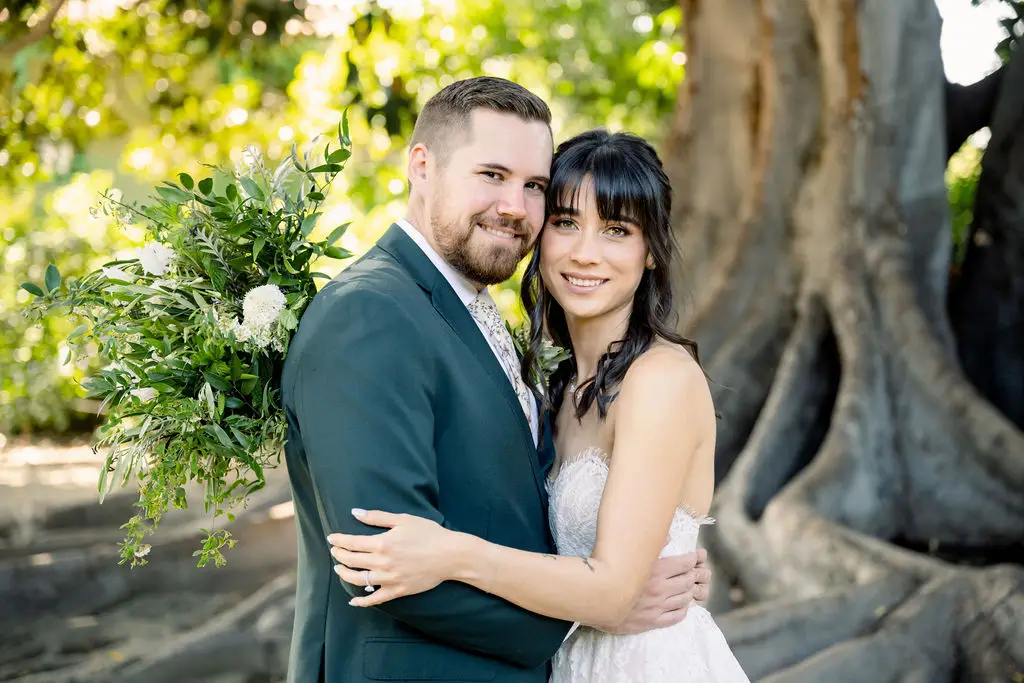 Bride and groom posing outdoors, smiling.