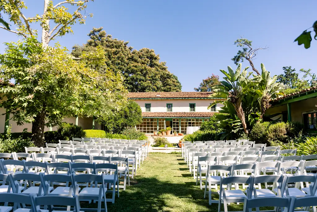 Outdoor wedding venue with white chairs and greenery.