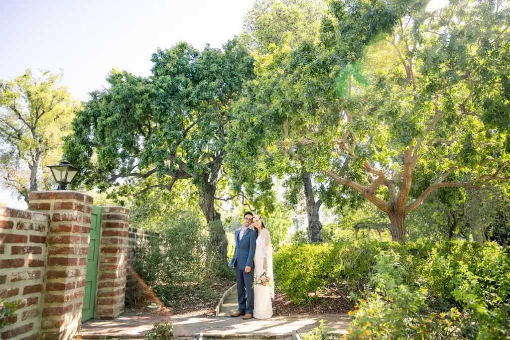 Couple posing under tree in garden.