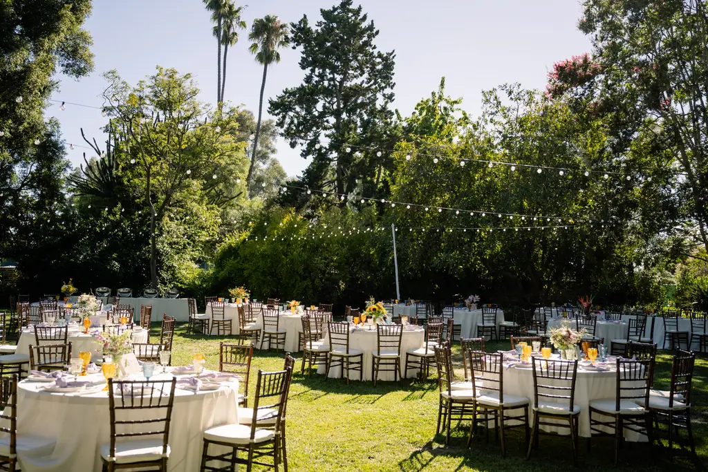 Outdoor wedding reception with decorated tables and chairs.