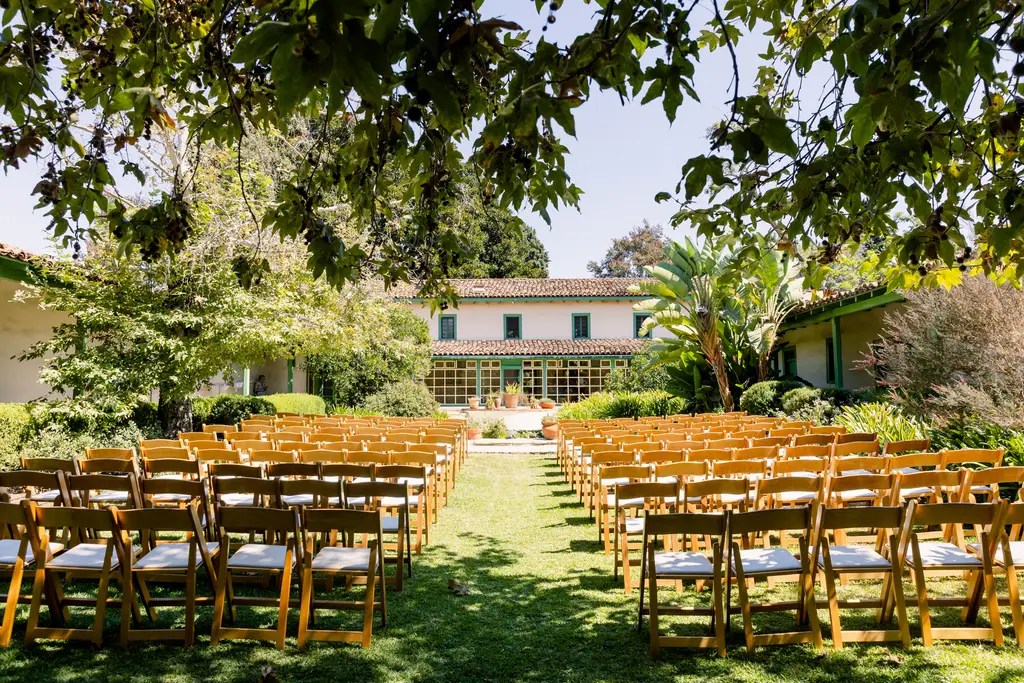 Outdoor wedding setup with chairs and greenery.