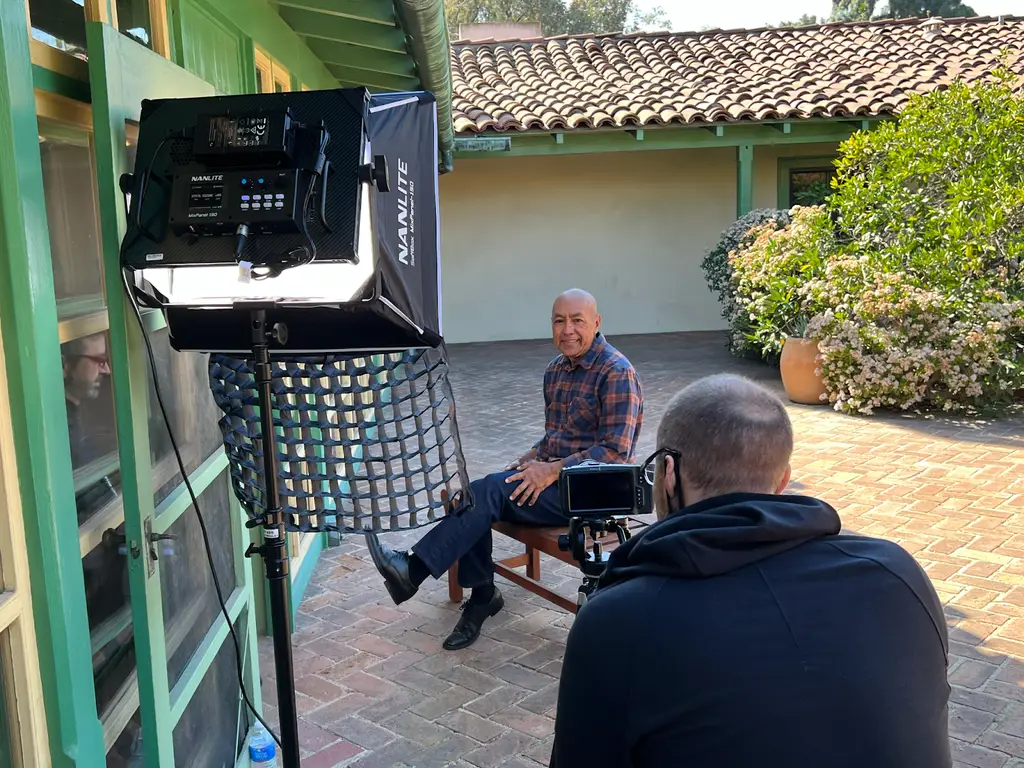 Man interviewed outdoors with professional lighting setup.