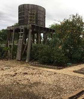 Old wooden water tower in rustic garden setting.